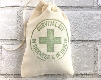 May include: A small off-white cotton drawstring pouch featuring a green circular stamp design. The print includes a central cross symbol and the text SURVIVAL KIT IN SICKNESS & IN HEALTH printed in a circular arrangement around the cross icon.