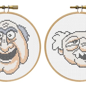 Könnte beinhalten: Zwei Kreuzstich-Stickrahmen mit dem Gesicht einer Zeichentrickfigur. Die Figur hat eine große Nase, große Augen und ein zahnreiches Grinsen. Die Stickerei ist in schwarzem, weißem und beigem Garn ausgeführt und in Holzreifen gefasst.