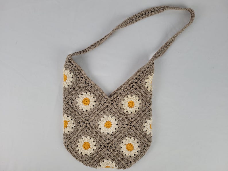 May include: A crocheted shoulder bag with a daisy pattern in beige and yellow.