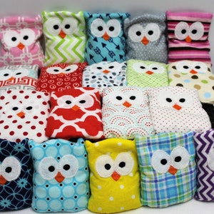 May include: A collection of 16 handmade owl-shaped bean bags in various colors and patterns, including red, green, blue, yellow, pink, and purple. Each bean bag features a white owl face with black eyes and an orange beak.