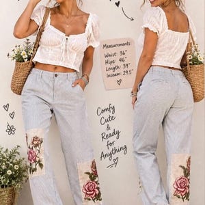 May include: Light blue and white pinstriped pants featuring floral patches on the lower legs and lace trim at the hems. The pants have a waist of 36 inches, hips of 46 inches, a length of 39 inches, and an inseam of 29.5 inches.
