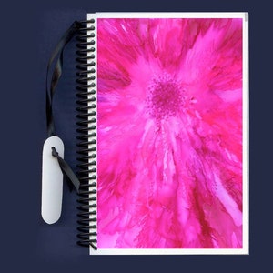 May include: A pink spiral bound journal with a black ribbon bookmark. The cover features an abstract pink flower design.