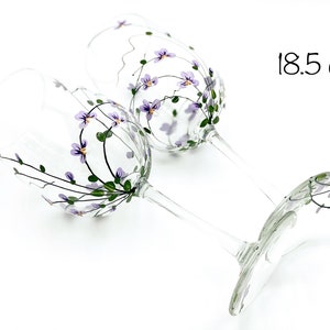 K&ouml;nnte beinhalten: Zwei handbemalte Weingl&auml;ser mit lila Blumen und gr&uuml;nen Bl&auml;ttern. Die Gl&auml;ser haben ein Fassungsverm&ouml;gen von 18,5 oz.