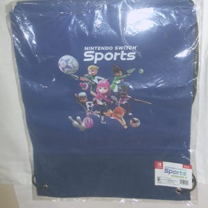 May include: A blue drawstring bag with a Nintendo Switch Sports logo and characters. The bag has a white drawstring and a white Nintendo Switch Sports logo on the bottom right corner.