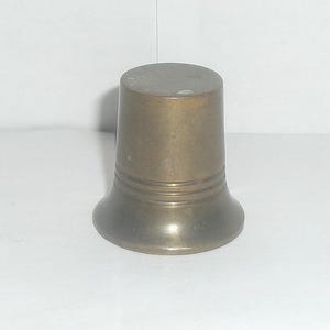 May include: A small, brass, bell-shaped object with a rounded top and a flared base. The object has a smooth, polished surface and a single band around the middle.