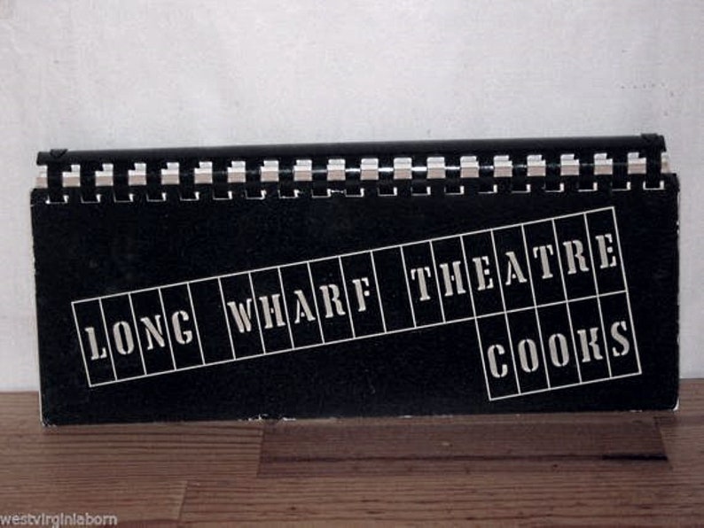 Puede incluir: Un letrero en blanco y negro con las palabras "Long Wharf Theatre" y "Cooks" en letras blancas.