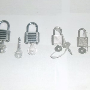 May include: Four silver padlocks with keys. Two padlocks have a silver body with a black stripe design. The other two padlocks have a solid silver body.