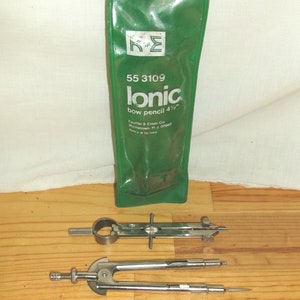 May include: A green plastic package containing a silver bow pencil labeled "lonic bow pencil 4 1/2" by the brand "K&E" with the model number "55 3109". The package is on a wooden surface with two silver compasses.