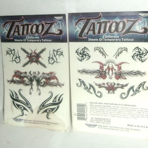 May include: Two sheets of temporary tattoos with tribal designs. The sheets are white with black and red designs. The text on the sheets reads "Tattooz 2 Different Sheets of Temporary Tattoos".