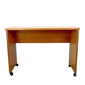 May include: A rectangular desk with a light brown wood grain finish. The desk features a flat top surface, two solid side panels, and a back modesty panel. Four small black caster wheels are attached to the base of the side panels for mobility.