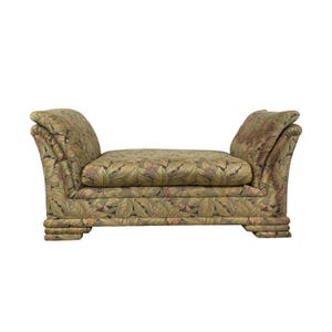 May include: A decorative bench with a leaf pattern in shades of green, brown, and gold. The bench has curved armrests and a rectangular seat. The base of the bench has a layered design. The bench is a piece of furniture.