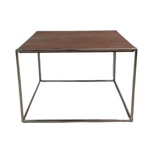May include: A modern square coffee table with a dark brown wood grain top and a silver metal frame. The table has a minimalist design, with clean lines and a geometric shape. The table is approximately 24 inches long, 24 inches wide, and 18 inches high.
