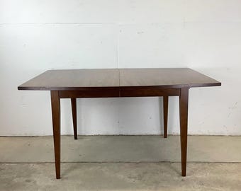 May include: A dark brown wooden dining table with a rectangular top and four legs. The table is made of solid wood and has a simple, elegant design.