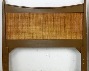 May include: A mid-century modern headboard with a woven cane center panel and a brown wooden frame. The headboard has a curved top and adjustable legs. The dimensions are approximately 60 inches wide and 40 inches tall.