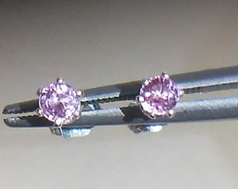 May include: A pair of silver stud earrings with small, round, pink gemstones.