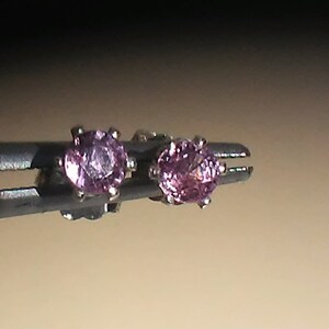 Pode incluir: Um par de brincos de prata com pedras preciosas cor-de-rosa.