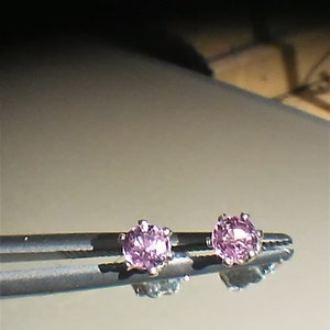 Pode incluir: Um par de pequenos brincos de pedras preciosas cor-de-rosa engastados em prata.