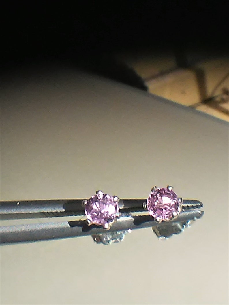 Pode incluir: Um par de pequenos brincos de pedras preciosas cor-de-rosa engastados em prata.