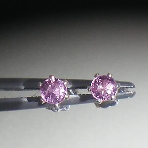 Pode incluir: Um par de brincos de prata com pedras preciosas cor-de-rosa.