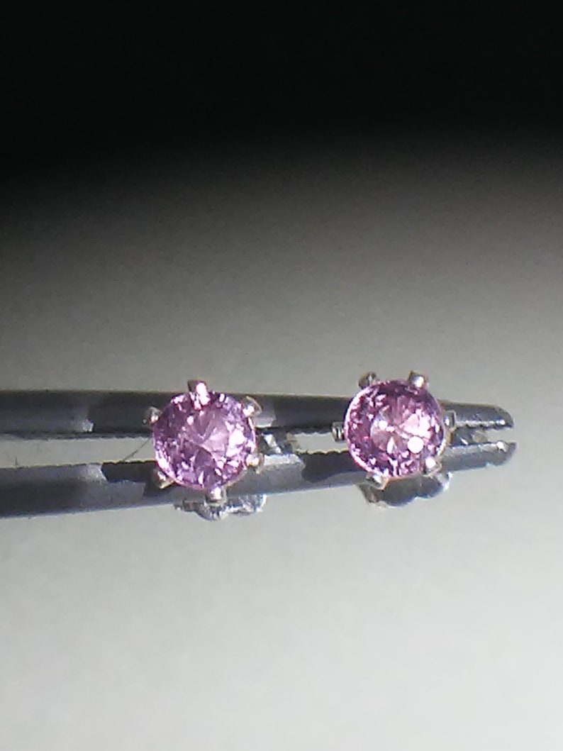 Pode incluir: Um par de brincos de prata com pedras preciosas cor-de-rosa.