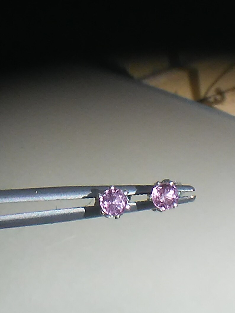 Pode incluir: Um par de brincos de prata com pedras preciosas cor-de-rosa.