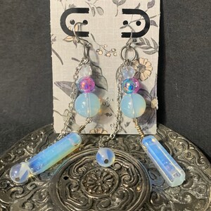 May include: A pair of silver chain earrings with iridescent blue and purple beads and opal-like stones.