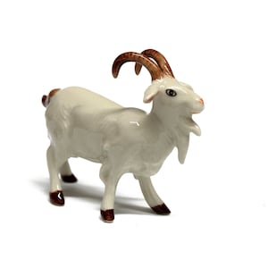 May include: A white ceramic goat figurine with brown horns and hooves. The goat is standing on all four legs and has a detailed face.