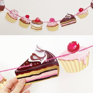 May include: A pink and white string of paper cupcake and cake decorations. The decorations feature different frosting and toppings, including cherries, strawberries, and chocolate.