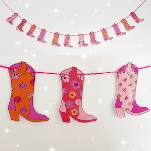 May include: A garland of pink and orange cowboy boots with a floral pattern. The garland is strung together with a white string.