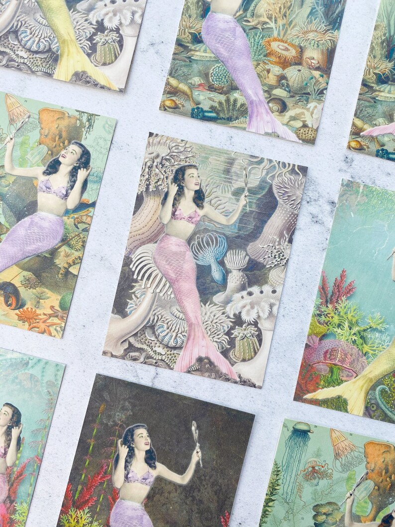May include: A set of vintage postcards featuring illustrations of mermaids in various underwater scenes. The mermaids are depicted with long flowing hair, wearing seashells and holding mirrors. The postcards are printed on thick cardstock and have a slightly textured surface.