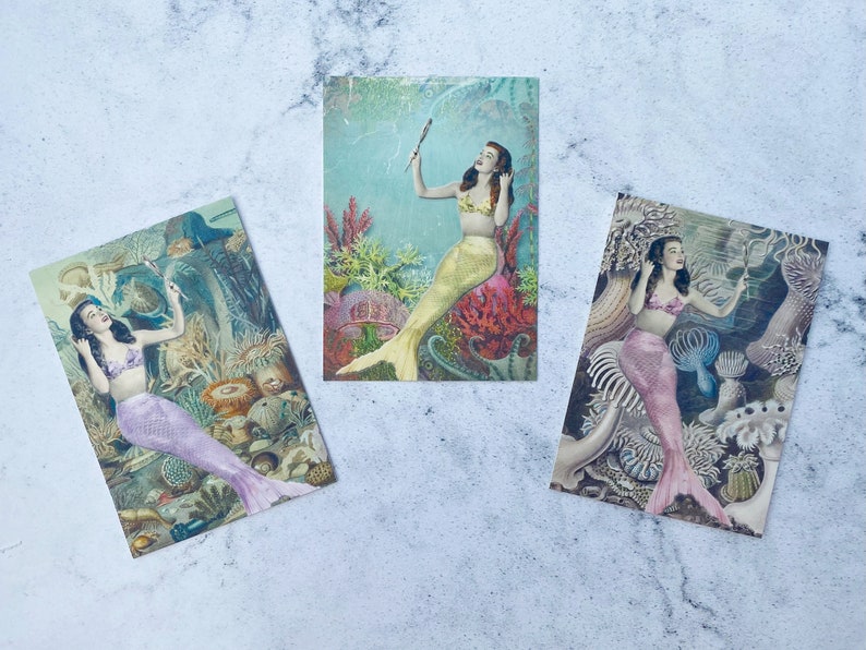 May include: Three vintage postcards featuring mermaids with colorful tails and underwater scenes. The mermaids are depicted with long flowing hair and are surrounded by coral, seaweed, and other marine life.