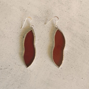 Könnte beinhalten: Ein Paar silberne Ohrringe mit roten gläsernen Anhänger in Tropfenform.