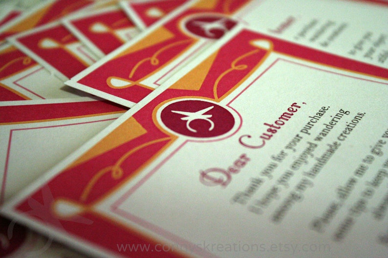Op de afbeelding: Een stapel bedankkaarten voor klanten met een rood, oranje en wit ontwerp. De kaarten bevatten de tekst "Dear Customer" en een logo. Het websiteadres www.comuskreations.etsy.com is zichtbaar.