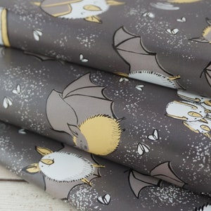 Op de afbeelding: Grijs cadeaupapier met een herhalend patroon van cartoonvleermuizen in grijs, geel en wit. De vleermuizen worden in verschillende poses getoond, met uitgespreide of gevouwen vleugels. Kleine witte, op insecten lijkende vormen zijn verspreid over de achtergrond.
