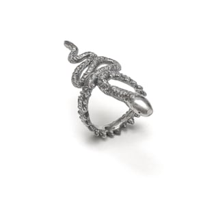 Pode incluir: Um anel de cobra de prata com um design detalhado. A cobra está enrolada em torno de uma banda com uma superfície texturizada.