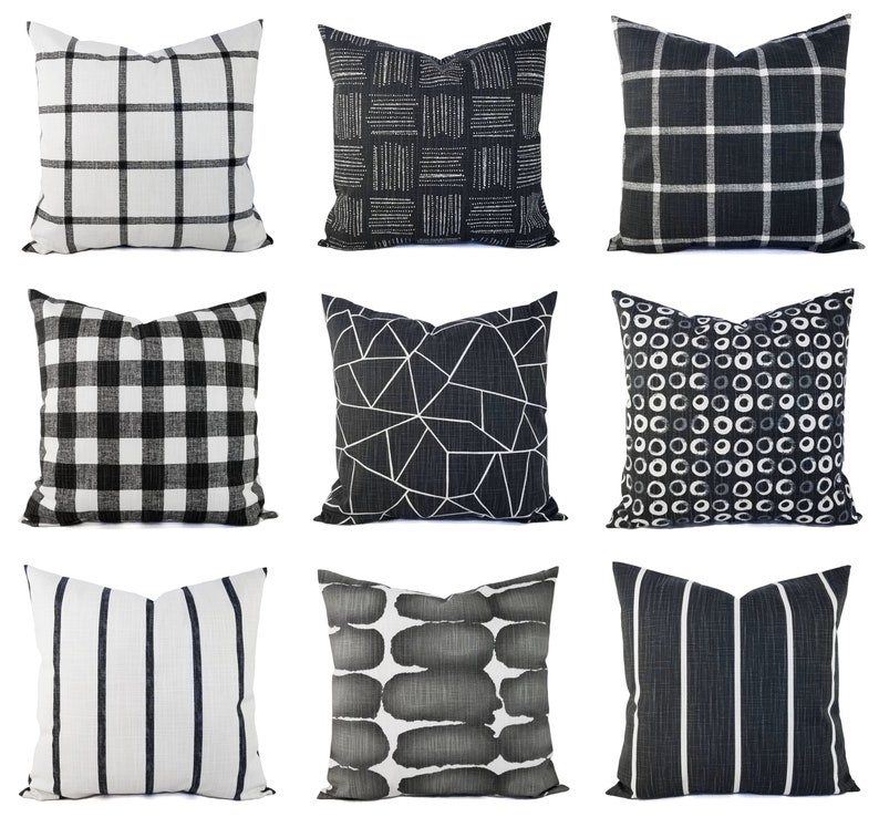 May include: A collection of nine square throw cushions featuring various black and white patterns including grid, plaid, buffalo check, geometric lines, circles, stripes, and abstract brushstrokes, all displayed against a plain white background.