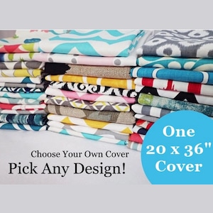 May include: A stack of colorful fabric swatches with various patterns, including chevron, geometric, and floral designs. Choose your own cover, pick any design! One 20 x 36" cover.