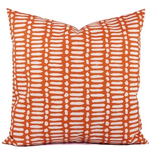 May include: Orange throw pillow with a white geometric pattern. The pattern is made up of horizontal rows of small, white ovals.