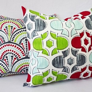 May include: Two decorative throw pillows with geometric patterns. One pillow features a red, green, and blue pattern with a white background. The other pillow features a white, gray, and red pattern with a green background.