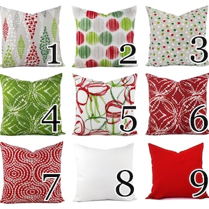 May include: A collection of nine square throw pillows featuring various patterns including red and green geometric shapes, polka dots, abstract circles, and solid white and red designs, each labeled with a large black number from one to nine.