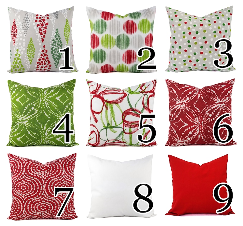 May include: A collection of nine square throw pillows featuring various patterns including red and green geometric shapes, polka dots, abstract circles, and solid white and red designs, each labeled with a large black number from one to nine.