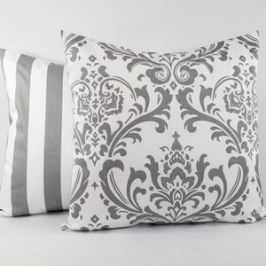 Pode incluir: Duas almofadas decorativas, uma com fundo branco e um padr&atilde;o damasco cinza, e a outra com listras brancas e cinzas.