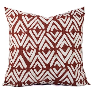 May include: A red and white throw pillow with a geometric pattern. The pillow is made of a soft, textured fabric.