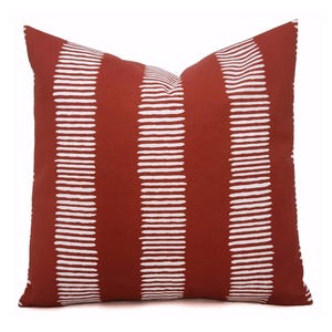 May include: A red throw pillow with white horizontal stripes. The stripes are made of small, white dashes.