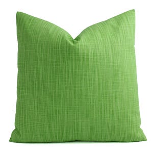 May include: A square, lime green throw pillow with a textured, woven appearance. The pillow has a solid color and a soft, inviting look, perfect for adding a pop of color to any room. The pillow is a decorative accent.