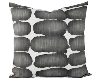 May include: Square decorative pillow with a white background and a pattern of large, dark gray, oval shapes. The shapes have a textured, brushstroke-like appearance, creating a modern, abstract design. The pillow is a neutral color, suitable for various decor styles.