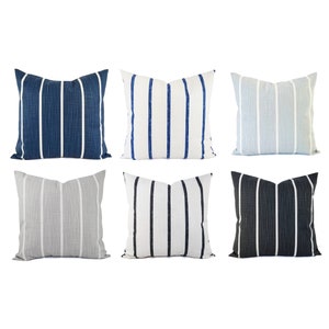 May include: Six decorative throw pillows with a striped pattern. The pillows are in various colors, including blue, gray, white, and black.