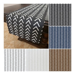 May include: A set of table runners with a chevron pattern in various colors, including black, navy, gray, and brown. The runners are made of a soft, durable fabric and are perfect for adding a touch of style to any dining table.
