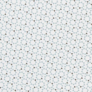 May include: White fabric with a repeating pattern of small blue triangles and brown circles. The fabric is measured with a ruler in inches.