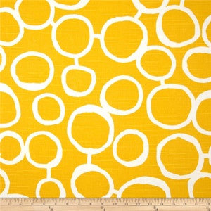 以下が含まれることがあります： 白い円の模様がついた黄色の生地。円はさまざまなサイズで、互いにつながっています。